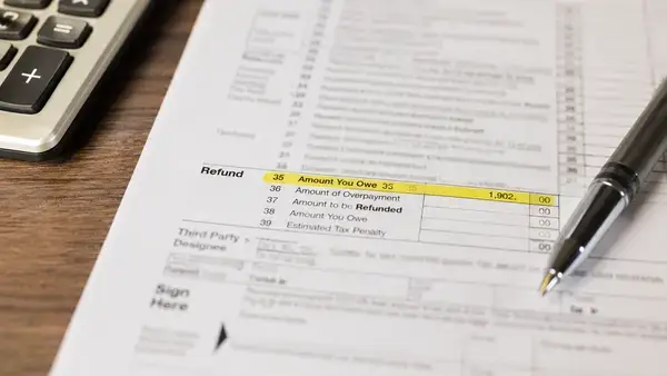 Tax return form showing a refund amount with a calculator representing missed IRS tax credits like EITC
