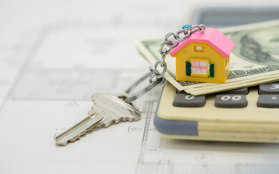 A miniature house above the bills and calculator.