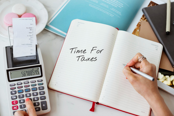 Hand writing in planner with calculator for tax preparation