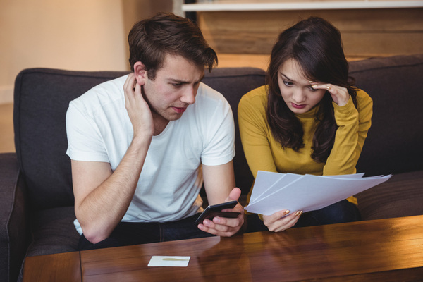 Couple reviewing documents and phone during tax preparation process
