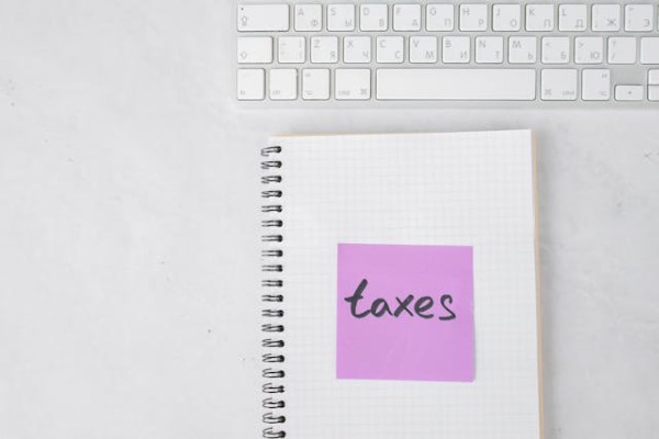 tax preparer's notebook with 'taxes' written on a sticky note next to a keyboard