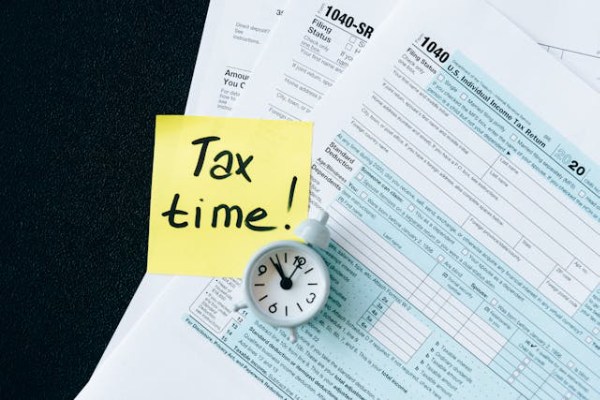 tax preparation reminder with tax forms, clock, and sticky note saying tax time