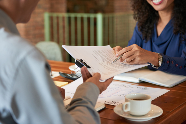 Two people reviewing papers to notarize a debt settlement agreement at table