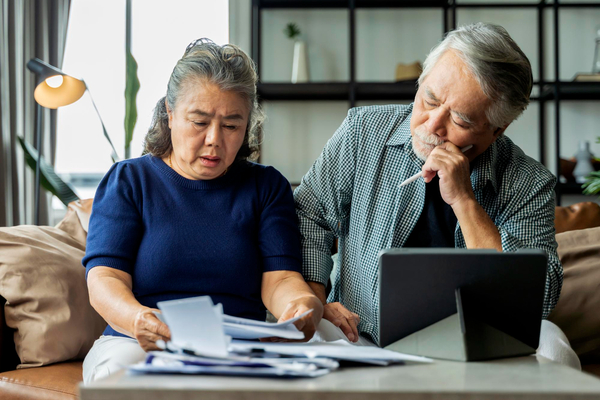 Senior couple reviewing documents and laptop for debt forgiveness program qualification options.