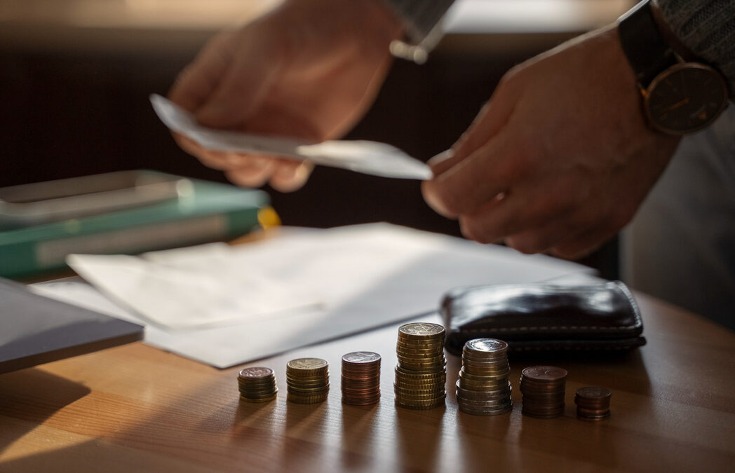 Person calculating taxes with coins showing red flags that trigger an IRS audit.