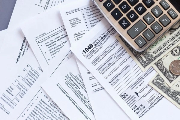 Federal tax forms and paperwork spread messily across a table.