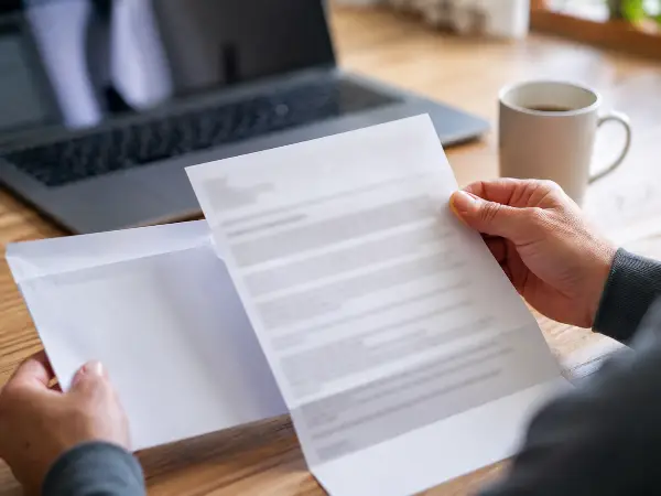 Hands holding an IRS notice envelope and letter over a desk